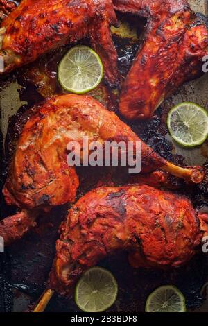 Indische Küche würziges rotes Tandoori-Hähnchen mit geschnittenem Kalk auf Backpfanne Stockfoto