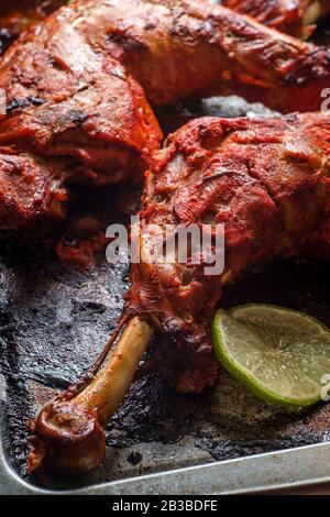 Indische Küche würziges rotes Tandoori-Hähnchen mit geschnittenem Kalk auf Backpfanne Stockfoto