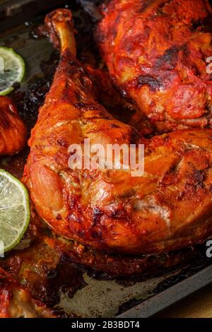 Indische Küche würziges rotes Tandoori-Hähnchen mit geschnittenem Kalk auf Backpfanne Stockfoto