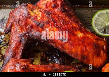 Indische Küche würziges rotes Tandoori-Hähnchen mit geschnittenem Kalk auf Backpfanne Stockfoto