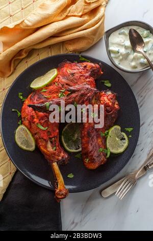 Indische Küche würziges rotes Tandoori-Hähnchen mit Gurken-Raita Stockfoto