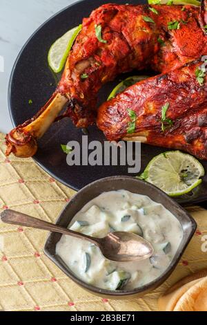 Indische Küche würziges rotes Tandoori-Hähnchen mit Gurken-Raita Stockfoto