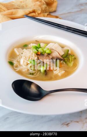 Schüssel mit geladener japanischer Miso-Suppe mit Nudeln Tofu gebrüllte Karotten und Zucchini Stockfoto