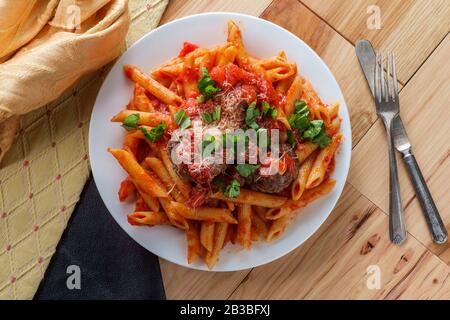 Italienische Penne reißende Pasta mit sugo all'arrabbiata Sauce und Fleischbällchen, garniert mit gehacktem Basilikum und Parmesankäse Stockfoto