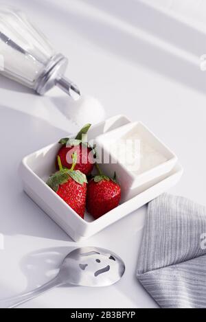 Frische Erdbeeren und Creme in eckigen weißen Schüsseln Stockfoto