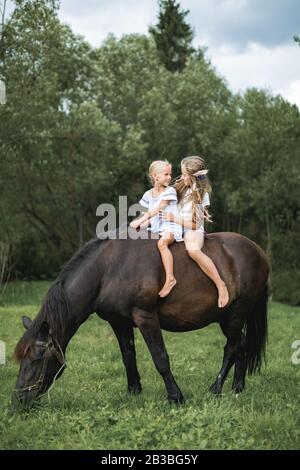 Kinder reiten in den Bergen. Familienurlaub auf der Pferderanch. Kinder reiten Pferd. Kind und Haustier. Kleine Mädchen haben Spaß beim gehen im Freien Stockfoto