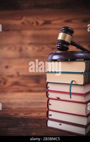 Stapel von Gesetzbüchern mit Richtergavel oben, Studiobild auf altem Holzhintergrund Stockfoto