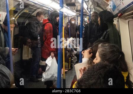 London, Großbritannien. März 2020. Ein Mann in einer Gesichtsmaske steht ganz am Ende der Rohrkutsche, während alle anderen ihre Reise ohne Masken Unternehmen, inmitten des Coronavirus Schreckens in London, Großbritannien, am 3. März 2020. Credit: Paul Marriott/Alamy Live News Stockfoto