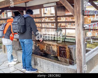 Anbeter am Chozua-Becken, die Hände und den Mund reinigen, bevor sie in den Shinto-Schrein kommen. Stockfoto