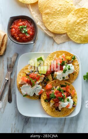 Mexikanisches Huhn tostada flaches Tacos mit Reis, schwarzen Bohnen, Salsa und saurer Sahne Stockfoto