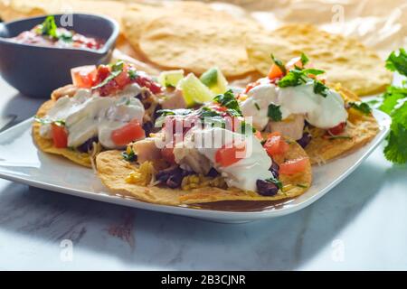 Mexikanisches Huhn tostada flaches Tacos mit Reis, schwarzen Bohnen, Salsa und saurer Sahne Stockfoto