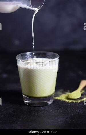 Heiße grüne Matcha Latte mit Mandelmilch auf schwarzem Hintergrund Stockfoto