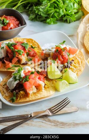 Mexikanisches Huhn tostada flaches Tacos mit Reis, schwarzen Bohnen, Salsa und saurer Sahne Stockfoto