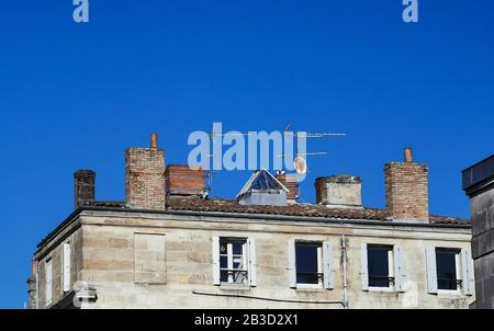 Altes Haus mit verschiedenen Arten von Kaminen und Antennen auf der Oberseite der Dächer gegen blauen Himmel Stockfoto