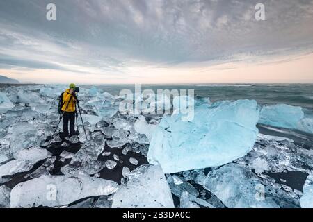 Fotograf am Diamond Beach, Eisberge am schwarzen Lava-Strand, in der Nähe der Gletscherlagune Joekulsarlon, Vatnajoekull National Park, Hornafjoerour Stockfoto