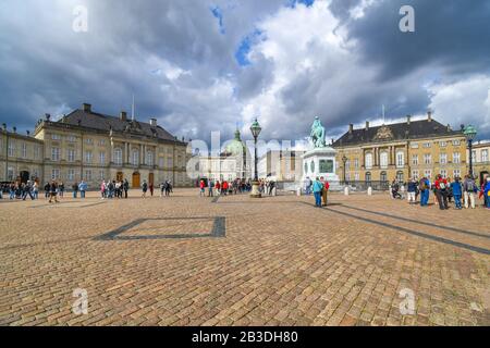 Touristen besuchen den Hauptplatz des Schlosses Amalienborg mit der Marmorkirche von Frederik und dem Reiterstandbild. Stockfoto