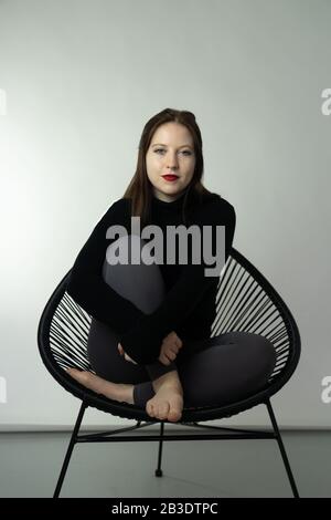 Young Woman Modeling im Studio Chair Stockfoto