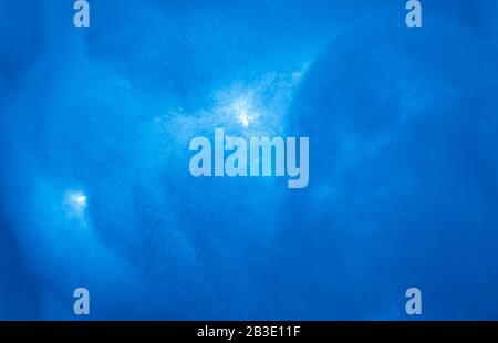 Eine Wolke, die aus medizinischer Baumwollwolle besteht und rot beleuchtet ist. Der abstrakte Hintergrund ist die Textur des blauen Himmels. Stockfoto