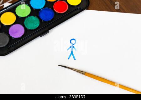 Der Mann ist mit Pinsel- und Aquarellfarben auf weißem Hintergrund bemalt. Karton mit Aquarellfarben und einem Pinsel zum Zeichnen. Stockfoto