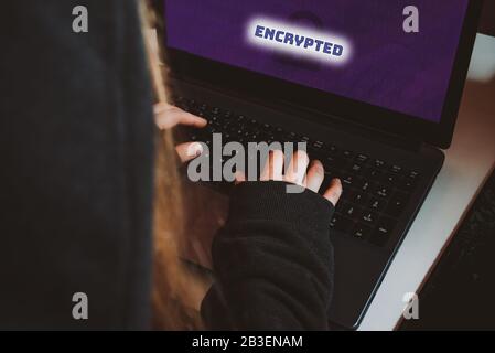 Frau in Hoodie, Hacker, die auf verschlüsseltem Laptop arbeiten, Draufsicht über das Tippen der Hände Stockfoto