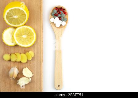 Zitrone, Ingwer und Kapelle gegen mehrfarbige Tabletten. Das Konzept der Wahl einer gesunden Ernährung im Gegensatz zur Einnahme von Medikamenten Stockfoto