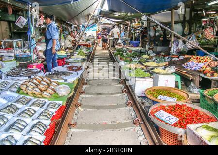 Händler auf dem einzigartigen Maeklong Wet Market verkaufen ihre Waren und Gemüse entlang der Maeklong Bahngleise Stockfoto