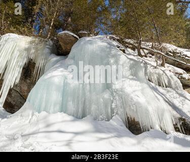 Wunderschöne, sonnenbeleuchtete Eiswände auf den Felswänden entlang eines Pfades im Algonquin Park Canada im März. Stockfoto