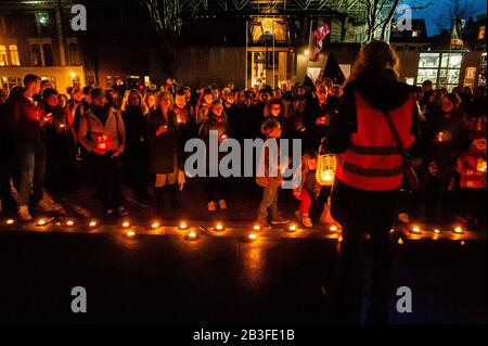 Die Leute, die während der Mahnwache Reden hören und Kerzen halten.Rund hundert Menschen versammelten sich auf dem Domplein in Utrechter, um eine Mahnwache zu halten, um ihre Solidarität mit den Flüchtlingen, Bewohnern der griechischen Inseln und NGOs zu zeigen. In der vergangenen Woche hat sich die Lage entlang der Grenze zwischen Türkisch-Griechenland deutlich verschlechtert. Migranten, die versuchen, Europa zu erreichen, haben sich gewaltsam mit der griechischen Bereitschaftspolizei getroffen, da die Türkei behauptete, dass mehr als 76.000 Menschen jetzt auf dem Weg zur EU waren, als Präsident Recep Tayyip Erdogan die Entscheidung traf, die türkische Seite der Grenze zu öffnen. Stockfoto