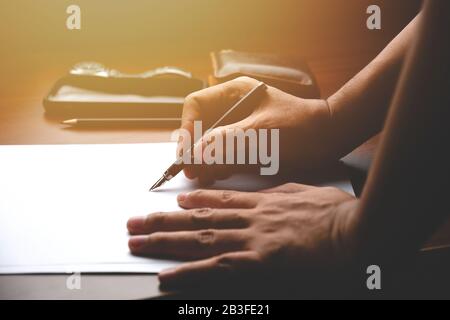 Der männliche Manager setzt seine Ideen ein und schreibt einen Geschäftsplan am Arbeitsplatz. Der Mann, der Bleistift hält, macht Notizen in Papierdokumenten auf dem Tisch im Büro Stockfoto