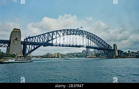 Die Sydney Harbour Bridge vom Wasser aus betrachtet, mit vier Gruppen von Touristen, die über den Bogen spazieren. Stockfoto