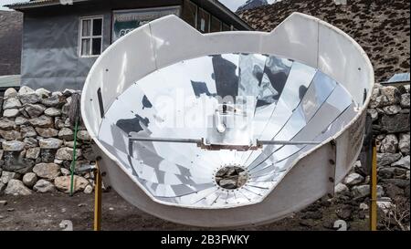 Dingboche, Nepal - 07. April 2018: Teekocherwärmung in einem Solarkocher im Hochland der Himalaya-Berge, Nepal; Nutzung erneuerbarer grüner Energie, ecolo Stockfoto