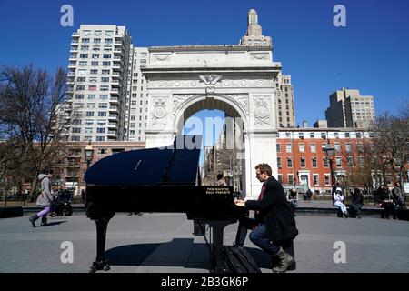 Ein Pianist, der mit Wood Guthrie's einen kleinen Flügel spielt Diese Maschine zu sagen, tötet Faschisten, die darauf geschrieben sind.Washington Square Park.New York City.USA Stockfoto