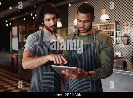 Café-Mitarbeiter arbeiten im Café mit einem digitalen Tablet zusammen Stockfoto