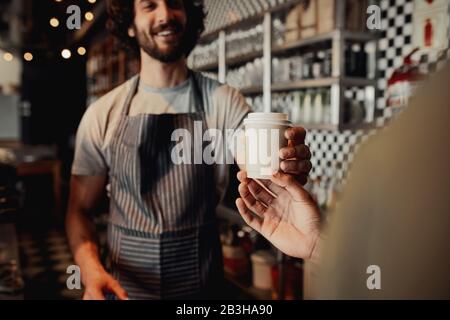 Kellner, der dem Kunden eine Tasse kalten Kaffee an der Theke im Café serviert Stockfoto