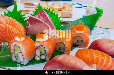 Japanische Kombination auf weißem Teller. Lachs-Sushi, Sashimi und Nigiri auf Restauranttisch. Fischfleisch in Scheiben geschnitten und Japan vinegared Reis rollt mit Stockfoto