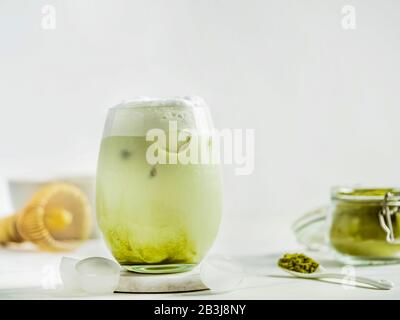 Iced Matcha Latte Tee mit Schlagsahne aus Tumbler Glas und Zutaten auf weißem Marmor Hintergrund. Kopierbereich für txt oder Design Stockfoto