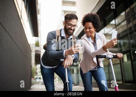 Junges Paar im Urlaub, das Spaß hat, mit Elektro-Roller in der Stadt zu fahren. Stockfoto