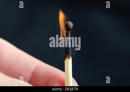Brennendes Spiel in der Hand vor schwarzem Hintergrund. Nahaufnahme Stockfoto