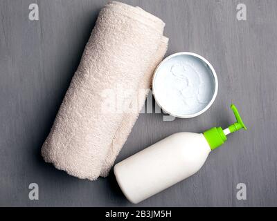 Flat Lay schöne Spa-Zusammensetzung Creme und Handtuch auf grauem Hintergrund. Hygiene und Hautpflegezubehör. Stockfoto