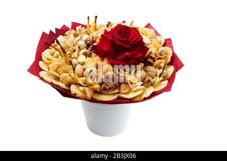 Großer Blumenstrauß aus exotischen Trockenfrüchten und Nüssen, dekoriert mit einer großen roten Rose, steht in einer Vase. Stockfoto