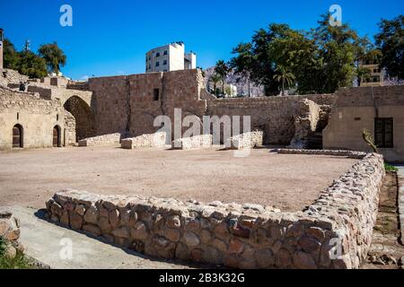 Aqaba, JORDANIEN - 31. JANUAR 2020: Touristen gehen an den Mauern der Festung. Blick auf den Innenhof der Burg Aqaba. Der Hauptplatz des Forts ist unter Sonnenlicht leer. Sonniger Wintertag. Klarer, wolkenloser blauer Himmel Stockfoto