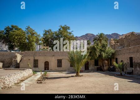 Aqaba, JORDANIEN - 31. JANUAR 2020: Touristen ruhen unter Mauern der Festung Schatten. Blick auf den Innenhof der Burg Aqaba. Der Hauptplatz des Forts ist unter Sonnenlicht leer. Sonniger Wintertag. Klarer, wolkenloser blauer Himmel Stockfoto