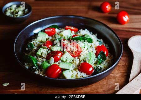 Gesunder Salat mit Bulgur, Avocado, Spinat und Kirschtomaten. Stockfoto