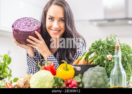 Verspielte junge Frau hält frischen Rotkohl in der Küche - Diät-Gemüse- und Heidekonzept. Stockfoto