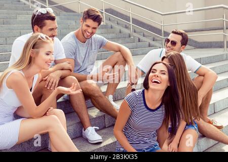 Eine Gruppe von Freunden, die auf einer Treppe sitzen, Spaß haben und lachen Stockfoto