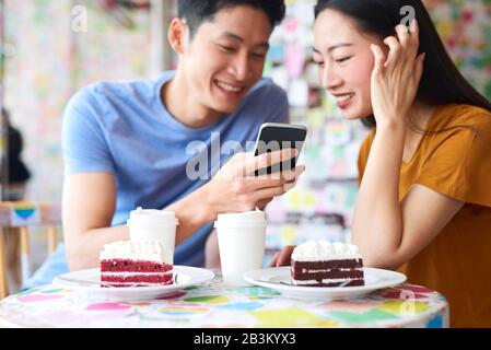 Aufgeregtes Paar mit Handy in einem Café Stockfoto