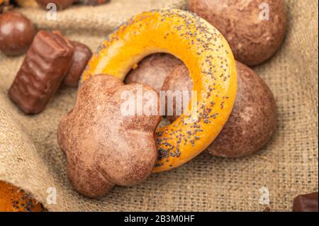 Bagels, Schokoladenkuchen und Schokolade auf dem Hintergrund rauer Homespun-Qualität. Nahaufnahme Stockfoto