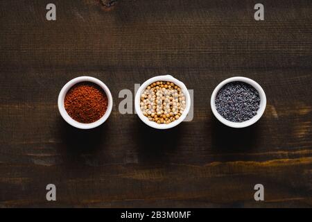 Verschiedene Gewürze auf dunklem Holzhintergrund. Gewürzsammlung Koriandermohn Sumac und Sesam. Asiatisches oder indisches Lebensmittelkonzept. Stockfoto