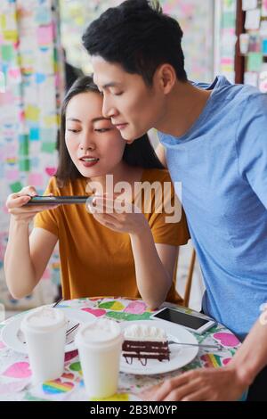 Vietnamesische Frau fotografiert ihr Dessert im Café Stockfoto