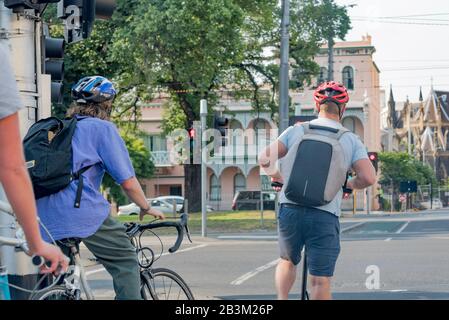 Radfahrer und Motorroller warten an einer Ampel auf ein grünes Signal an der Brunswick Street, Fitzroy, während sie in Richtung Stadt pendeln. Stockfoto